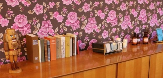 Holzkommode vor Blumentapete mit Nussknacker und Büchern